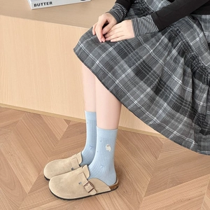 Détail de chaussettes en coton bleu clair avec broderie chat et sabots en daim