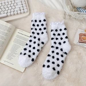 Detailed view of white polka dot coral fleece socks with elegant ruffled edges for winter