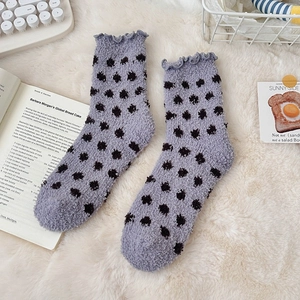 Detail of lavender fuzzy socks with dark dots and lettuce trim on soft plush surface