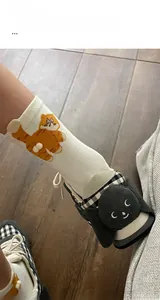 Detail of cream knitted socks with orange cat embroidery and 3D plush balls on socks