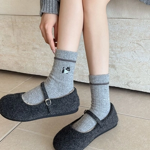 Détail de chaussettes grises côtelées avec broderie chat et chaussures Mary Jane