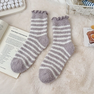 Detailed close-up of striped coral fleece socks with ruffled cuffs on soft carpet