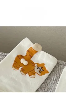 Detail of white cotton sock with cartoon orange cat and 3D plush pom-poms on the side