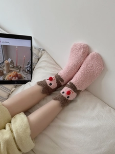 Detail of pink coral fleece socks featuring 3D cartoon reindeer with a red pom-pom nose