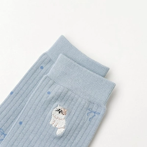 Détail de chaussette en coton bleu clair avec bord-côte et broderie de chat blanc