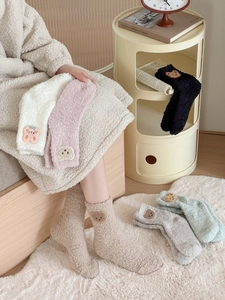 Close-up of fluffy coral fleece socks with cute bear embroidery in various soft colors