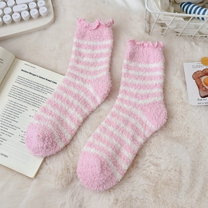 Detail of pink and white striped coral fleece socks with ruffled edges on plush carpet