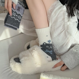 Détail de chaussettes en laine jacquard chat avec pantoufles en fausse fourrure blanche