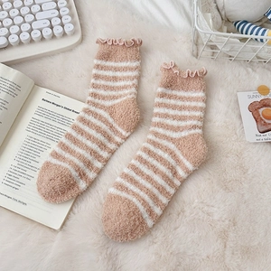 Close-up of striped coral fleece socks with ruffled edges on a soft plush blanket
