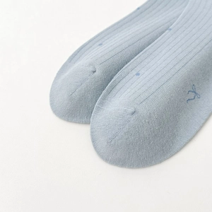 Gros plan de chaussettes en coton bleu clair côtelé avec pois et petit nœud délicat