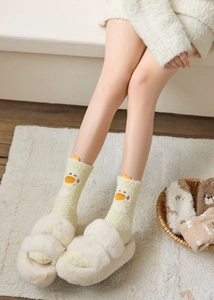 Close-up of cozy coral fleece socks with cute cartoon duck embroidery and plush slippers