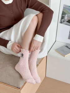 Close-up of pink coral fleece socks featuring black flower embroidery and Beautiful text