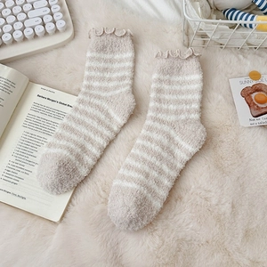 Detail of striped coral fleece socks with wavy edges on white soft faux fur background