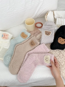 Detail of coral fleece socks with cute bear embroidery in various soft colors