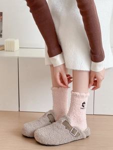 Detail of plush fleece slippers and pink coral velvet socks with floral embroidery