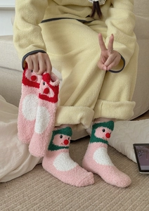 Close-up of pink coral fleece socks with 3D red plush balls and soft texture