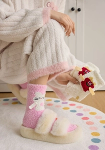 Close-up of pink coral fleece socks and plush slippers with a cute rabbit design