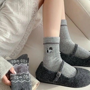 Détail de chaussettes en laine Fair Isle grises avec broderie chat et motifs flocons