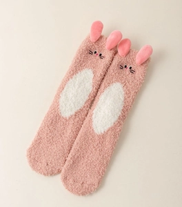 Détail de chaussettes en polaire corail rose avec oreilles de lapin 3D et broderie