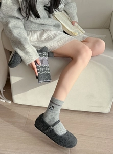 Détail de chaussettes en laine grises avec broderie chat et motif flocon pour l'hiver