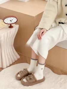 Detail of coral fleece socks with heart embroidery and plush slippers for home