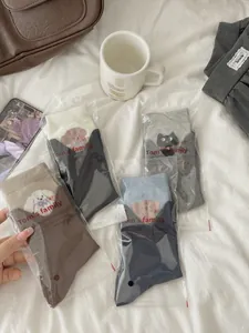 Close-up of four pairs of cotton socks with cute animal embroidery in retail packaging
