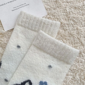Gros plan de chaussettes en peluche blanches à motifs Fair Isle bleus et noirs