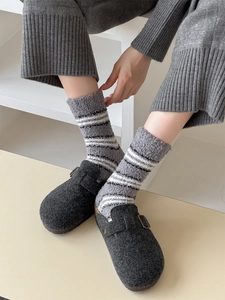 Detail of grey striped coral fleece socks worn with wool clogs on a minimalist background