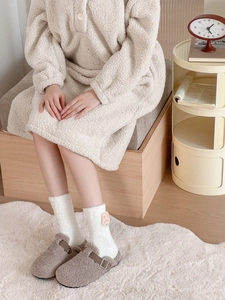 Detail of plush coral fleece socks with cute 3D bunny patch and fuzzy white texture