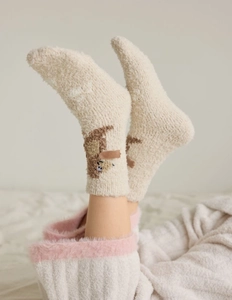 Detail of coral fleece sock showing brown cartoon bear embroidery on beige fabric