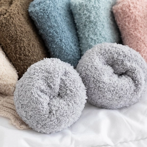 Thick coral fleece socks for winter in multiple soft colors on a white cotton surface