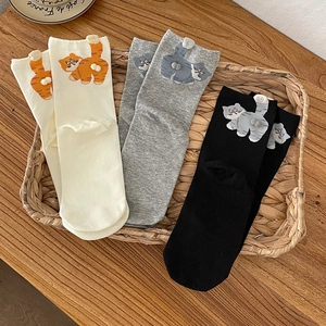 Three pairs of cute cartoon cat cotton crew socks with 3D pompoms in a rustic basket