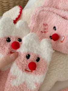 Close-up of pink coral fleece socks featuring cute cartoon beaver embroidery detail
