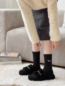 Detail of plush black coral fleece socks and matching slippers with cute dog embroidery