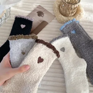 Detailed view of plush coral fleece socks with embroidered heart and wavy cuffs