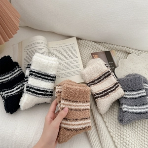 Close-up of five colorful striped coral fleece winter socks on a cozy knit blanket