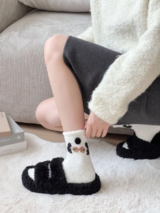 Detail of warm white fuzzy socks with emoji patterns and thick plush winter slippers