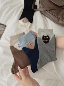 Close-up of five pairs of cotton socks with cute animal embroidery and folded cuffs