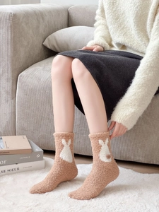 Close-up of thick coral fleece winter socks featuring 3D pom-pom and rabbit pattern detail