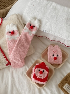 Close-up of pink coral fleece socks featuring cute cartoon beaver and red pom-poms