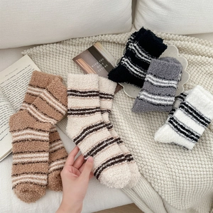 Detail of coral fleece striped socks in multi-color pile on a white textured blanket