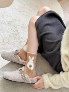 Detail of winter coral fleece socks with rabbit pattern and cozy sherpa lined slippers