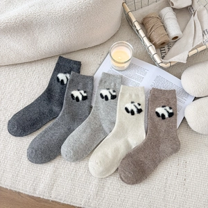 Dettaglio di cinque paia di calze di lana spesse con simpatici panda in peluche applicati