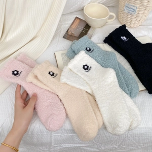 Close-up of fluffy coral fleece socks with elegant 3D flower and pearl embroidery detail