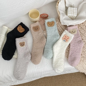 Detailed macro view of six colorful coral fleece socks with cute animal embroidery