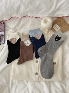 Detailed view of cute cat and dog embroidered motifs on cotton ribbed mid-calf socks