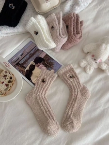 Detail of plush winter coral fleece socks featuring cute bear embroidery and ribbed texture