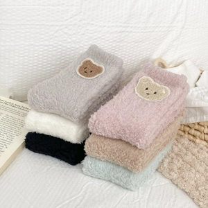 Detailed view of thick coral fleece socks with cute cartoon bear patches in various colors