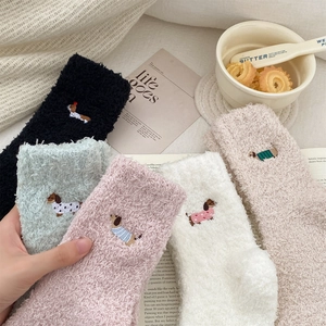Detail of coral fleece socks featuring puppy embroidery in a cozy home setting
