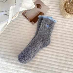 Close-up of fluffy grey coral fleece socks with blue heart embroidery and wavy edge